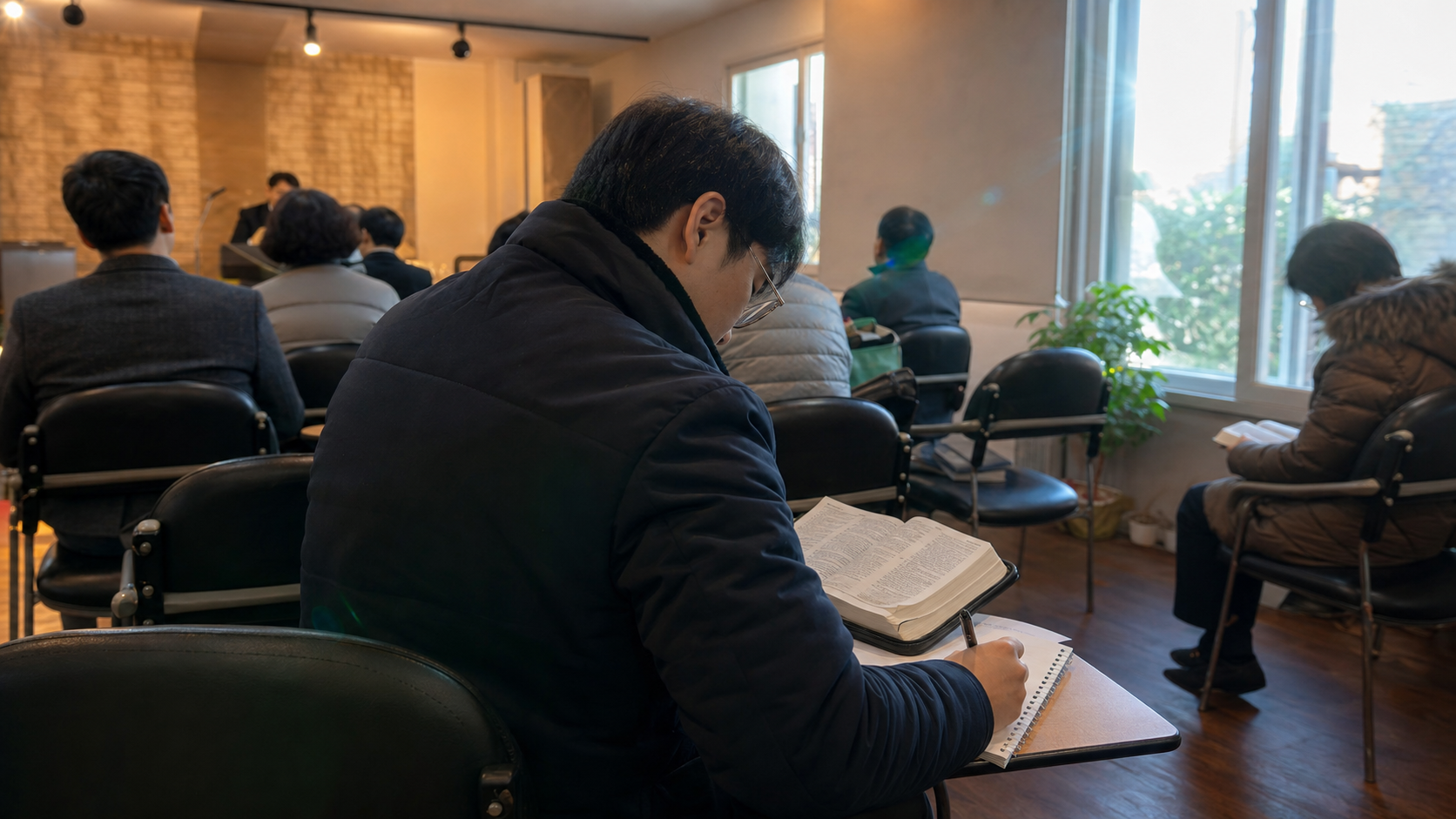 수요일 저녁 예배 자리에서 성경을 펴고 메모하며 말씀을 듣는 장면으로, 수요예배의 차분한 분위기를 보여줍니다. — 수요예배의 기본 의미(수요예배에 대해 자주 묻는 질문과 알아둘 점) 내용을 보여주는 사진