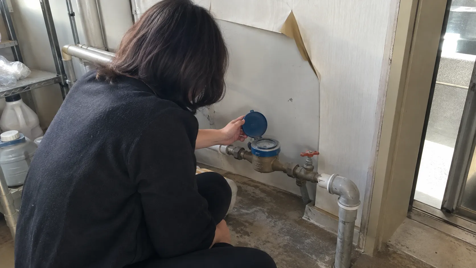 수도 계량기를 확인하는 동안 벽지 가장자리가 들뜨고 벽면 일부가 변색된 실내 모습을 보여 주며, 물방울이 없어도 발생 위치와 사용 조건을 기록하는 과정을 설명합니다.