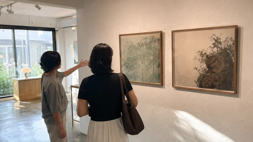 관람객이 미술관에서는 전시 전체의 주제와 작품 설명을 읽고 화랑에서는 작가 문장과 작품 배열을 살피며 두 공간의 소개 방식 차이를 비교하는 장면입니다.