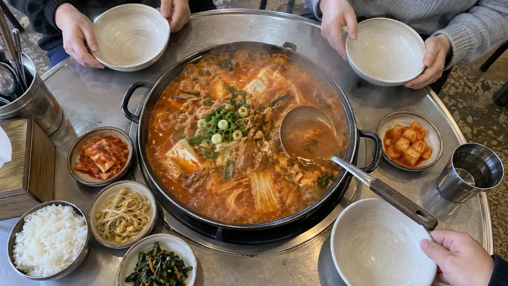 전골 냄비를 가운데 두고 3명이 국자로 건더기를 덜어 각자 앞접시에 나누는 모습으로, 인원수와 밥 곁들임에 따라 양을 판단하는 장면을 보여줍니다.
