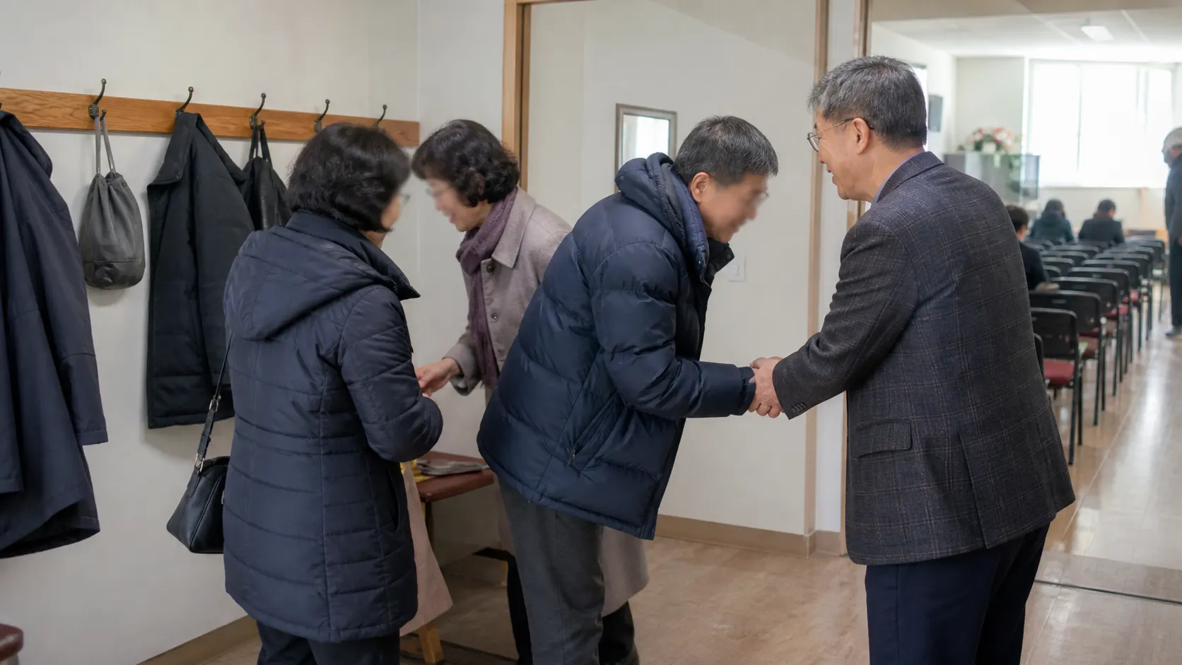 예배를 마친 사람들이 평범한 출입구 주변에서 서로 인사를 나누고, 옆자리의 표정과 몸짓이 온라인 화면과 다른 관계의 시작과 후속 대화를 보여주는 장면입니다.